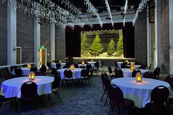 Event hall set up with round tables and lighting.